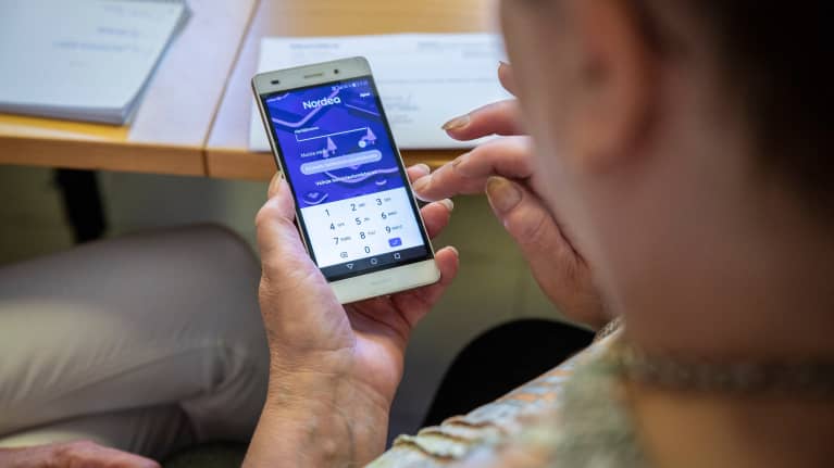 La mujer utiliza Nordea Online Banking a través de una aplicación instalada en su teléfono móvil.