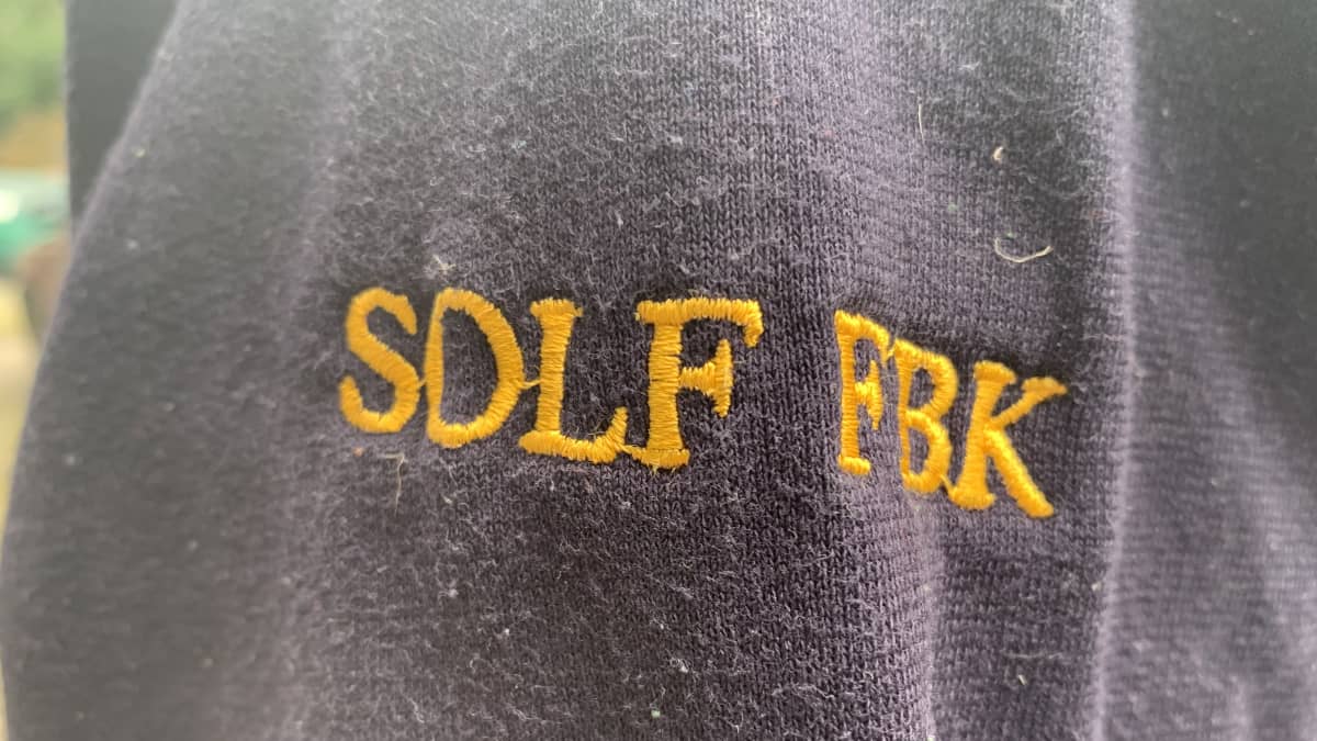 Ärmen på en mörkblå tröja där namnet Solf FBK står skrivet i gult.