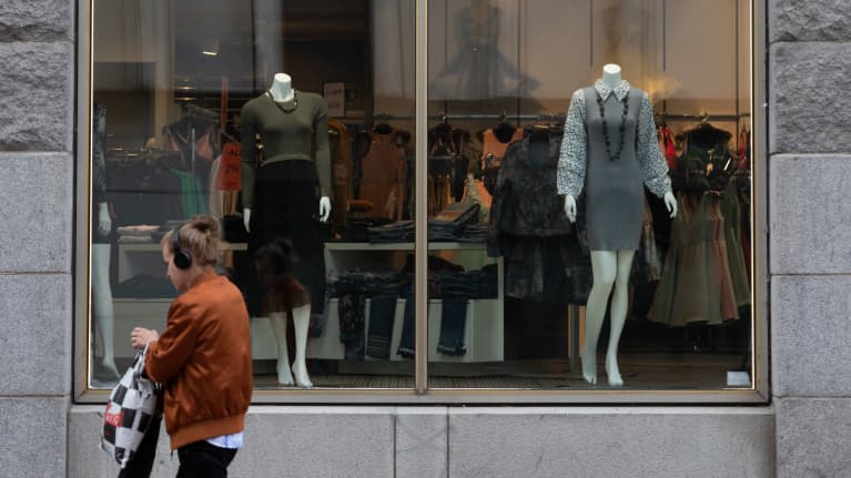 Henkilö kävelee liikkeen näyteikkunan ohi.