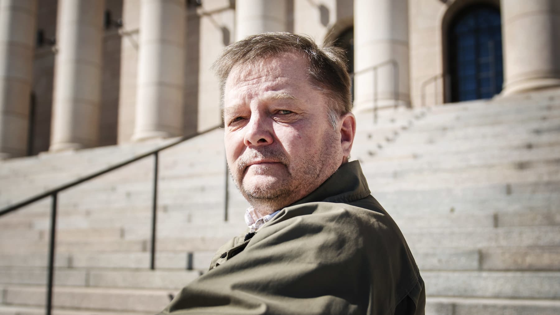 Vasemmistoliiton kansanedustaja Markus Mustajärvi istuu Eduskuntatalon edessä.