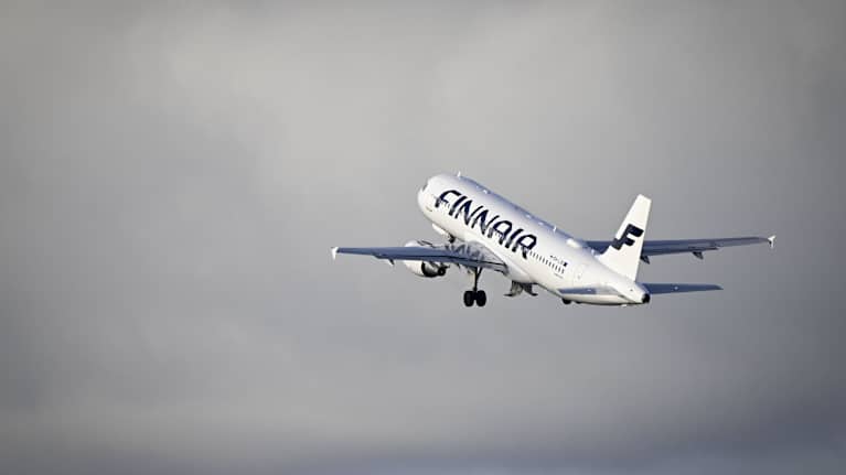 White passenger jet emblazoned with the word "Finnair" and the airline's logo, in blue. The plane is taking off into a grey sky.