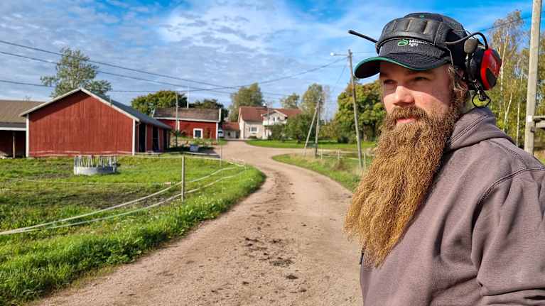 En bonde står framför sitt hus.