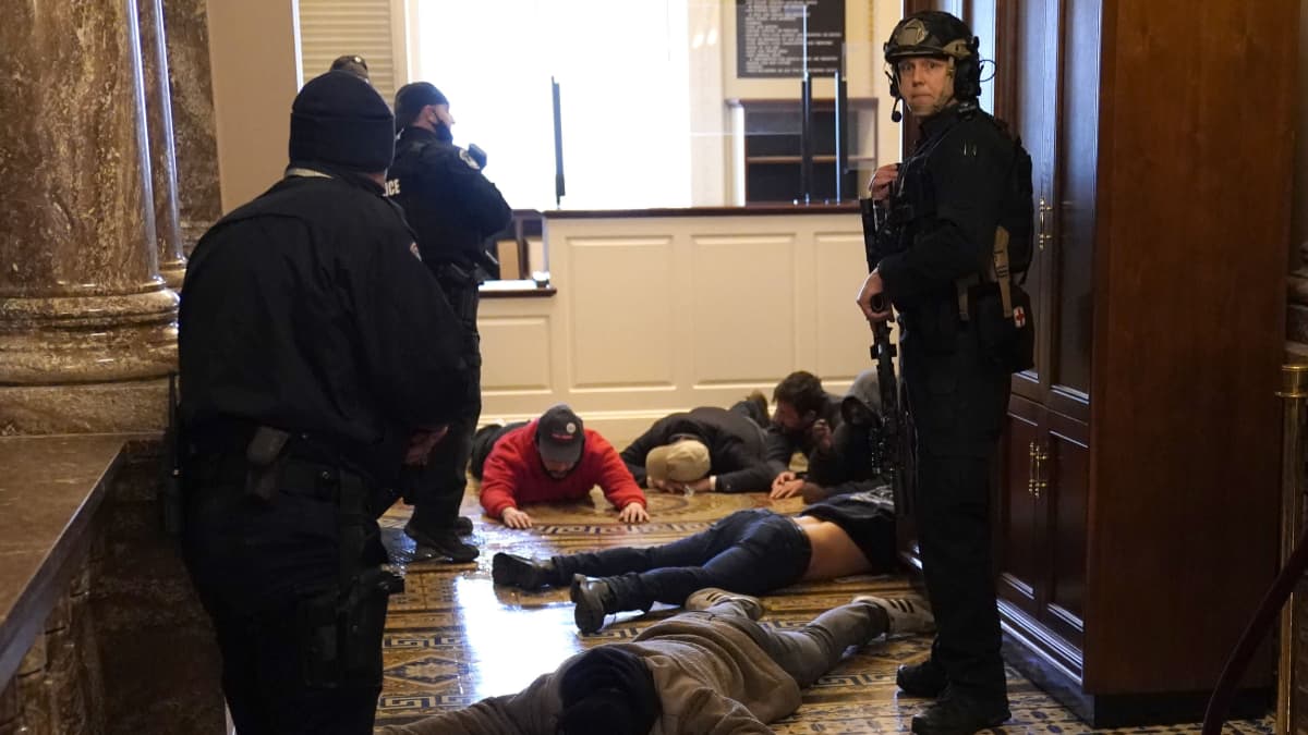 Poliisin kiinniottamia protestoijia kongressitalolla.