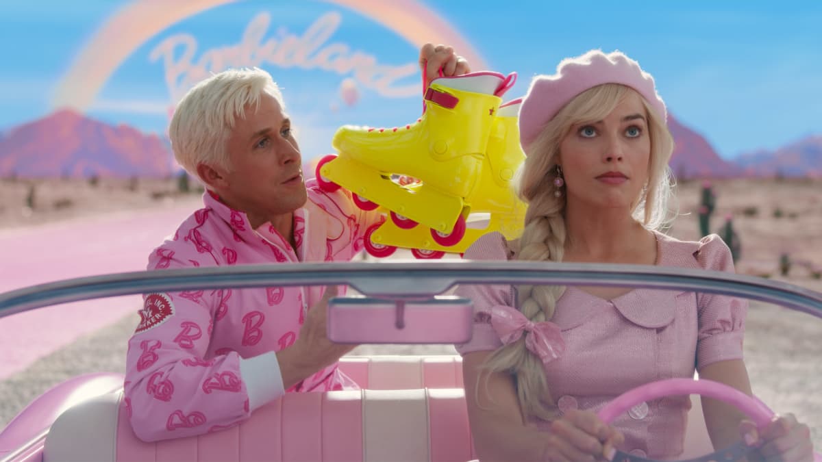 Auton takapenkillä istuva Ken esittelee rullaluistimilla auton ratissa olevalle Barbielle.