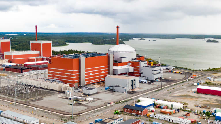 Aerial photo of the Olkiluoto 3 nuclear power station, a group of large red and white buildings and infrastructure.