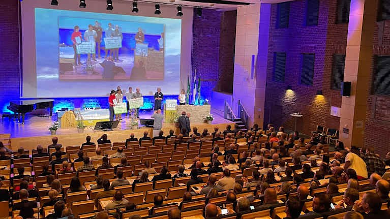 En konferens med en stor publik i en aula. På scenen delar personer ut priser 