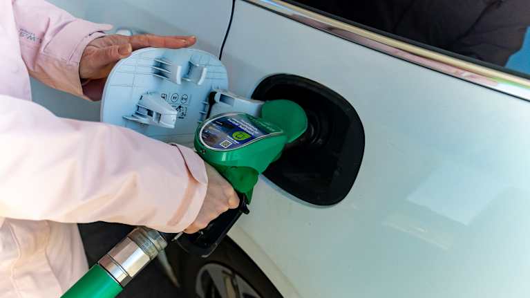 Close up photo of a person pumping gas into a car.