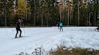 Image: Four people skiing on the first snow track in Imatra. Some trees in the background still have leaves on them.