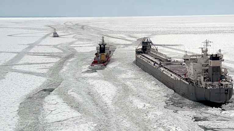 small icebreaker breaks ice for a tanker.