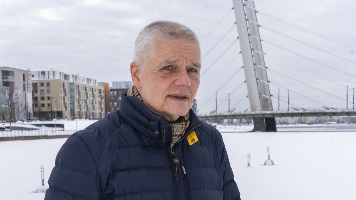 Esittelijäneuvos Tapio Räty nojaa kaiteeseen Ruoholahden kanavan vieressä ja katsoo kameraan.
