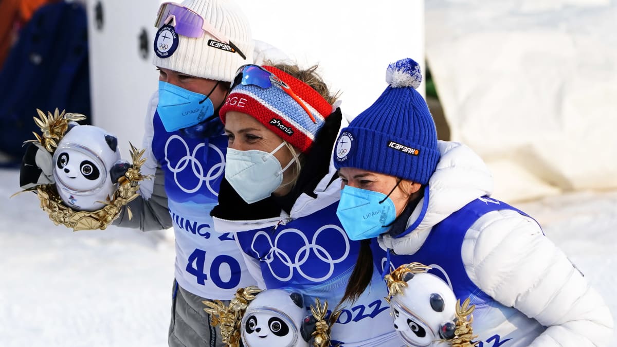 Kerttu Niskanen (vas.), Therese Johaug ja Krista Pärmäkoski poseeraavat lehdistölle kisamaskotit käsissään.