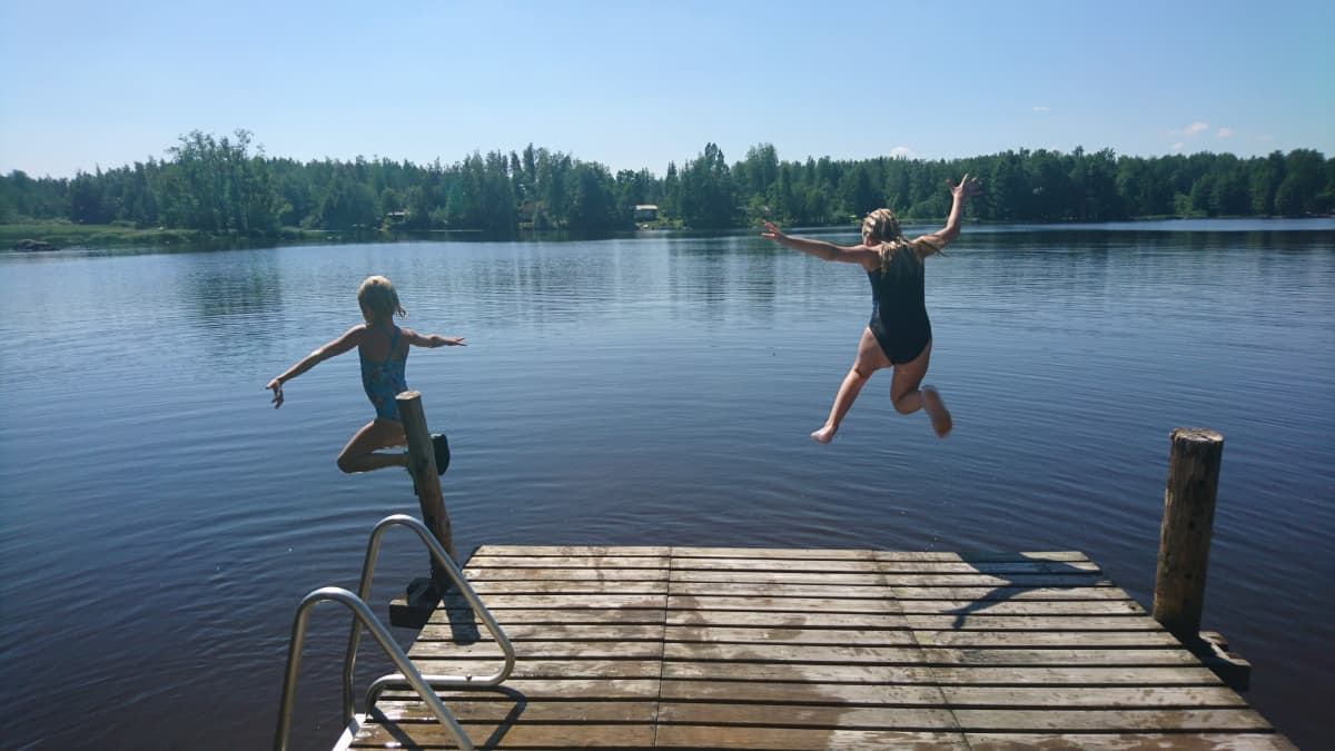 Tyttöjä uimassa järvellä helteellä. Tytöt hyppäävät järveen.