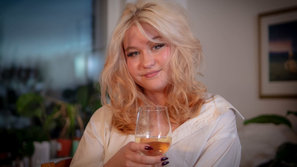 Marjukka Ruotsalainen hynyilee viinilasi kädessään.