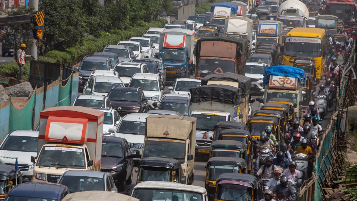Iso liikenneruuhka Intiassa, keskellä autoja, oikeassa laidassa moottoripyöriä ja mopoja. 