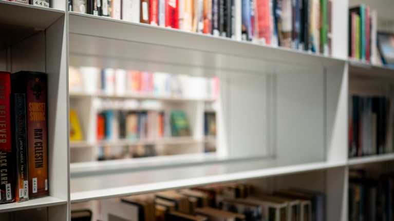 Tyhjä kirjahylly. Muut hyllyt ympärillä ovat täynnä kirjoja.