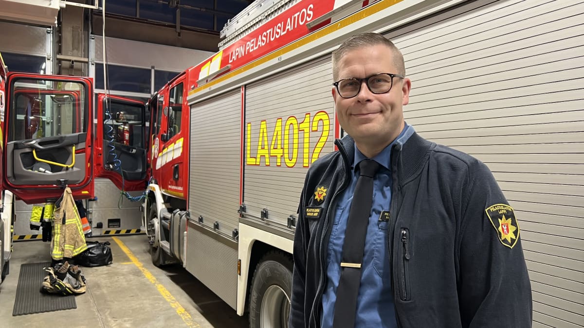 Pelastuslaitoksen siniseen takkiin pukeutunut pelastusjohtaja Markus Aarto  Lapin pelastuslaitokselta seisoo paloauton sivulla paloasemalla.