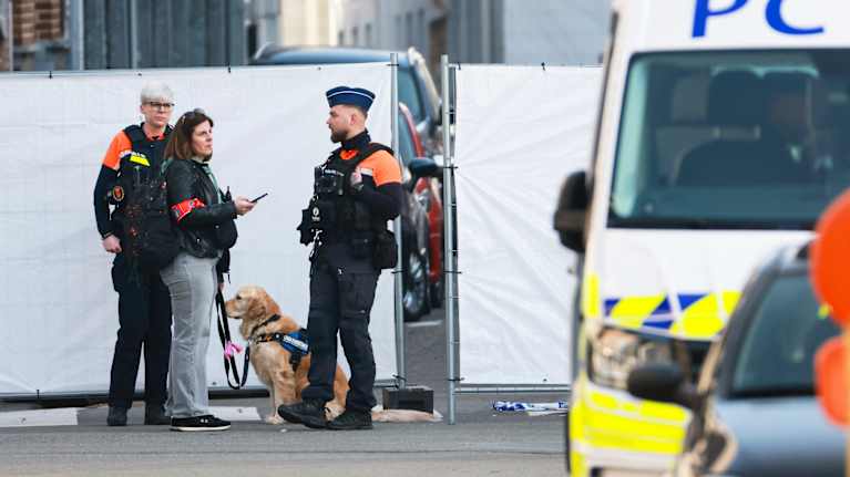 Kolme poliisia ja poliisikoira seisoo poliisiauton vieressä.
