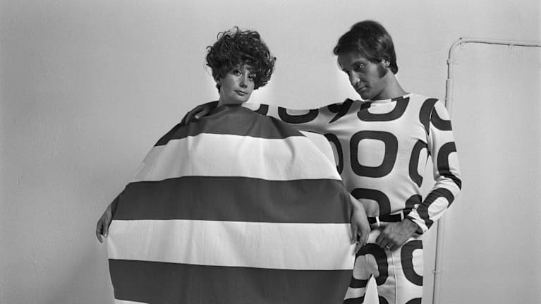 Naismallilla on yllään pyöreä Myllynkivi-mekko, miehellä housupuku Rengas-kankaasta. Molemmat asut on suunnitellut Vuokko Nurmesniemi 1960-luvulla.