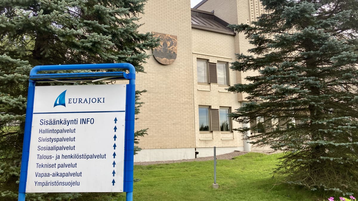 Vaaleatiilisen rakennuksen edessä kyltti, jossa lukee Eurajoki ja siinä on infoa kunnan palveluista.