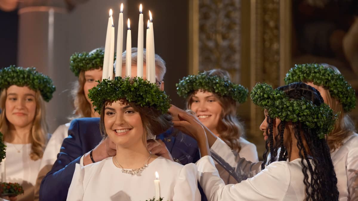 Lucia-neito Madeleine Amoroso sai päähänsä kynttiläkruunun. Kuva: Yle / Marcus Rosenlund