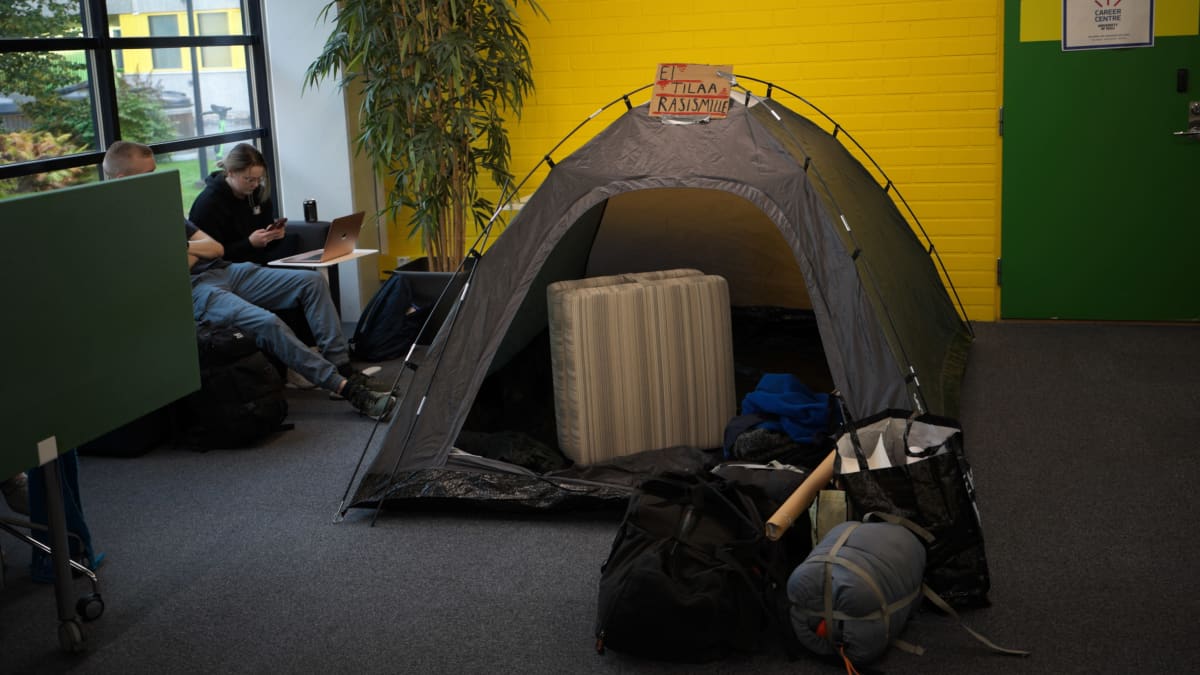 Photo shows a tent at Oulu University with a sign on top saying "No space for racism"