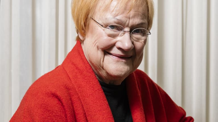 Presidentti Tarja Halonen poseeraa valokuvassa punaisessa jakussa.