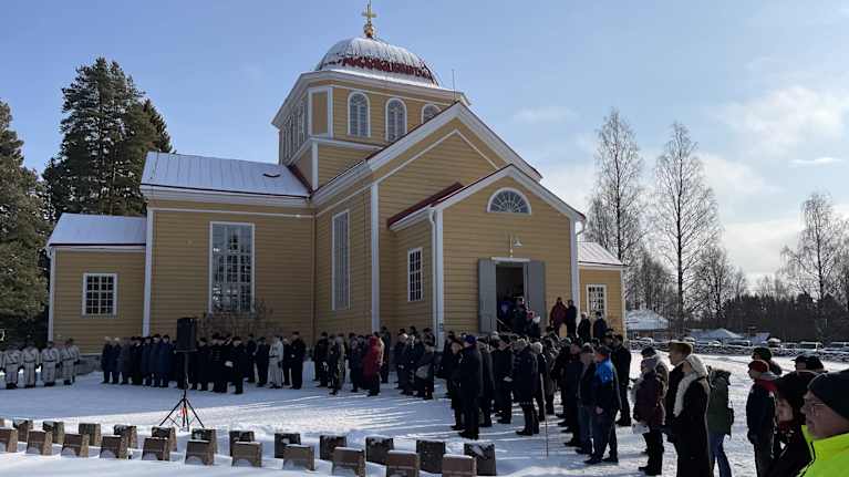 Parikkalan Uukuniemen puinen keltainen kirkko talvella ja yleisä lkerääntyneenä sen avoimein ovien edustalle.
