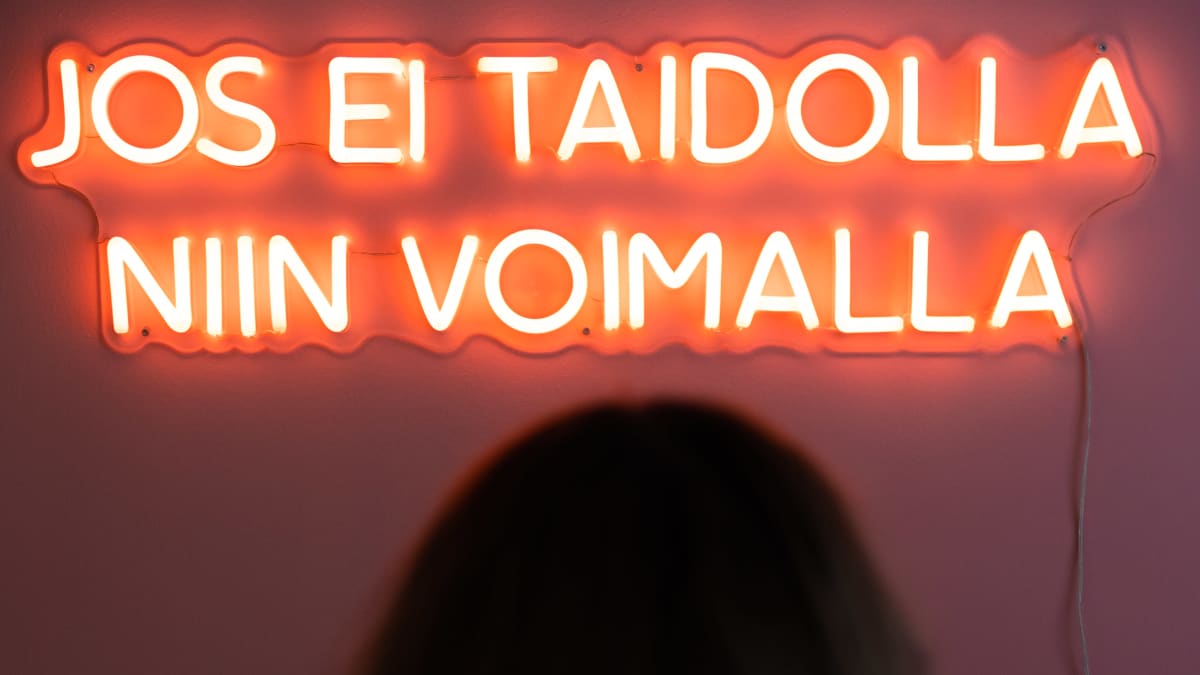 Neonvalo seinällä, jossa lukee "jos ei taidolla, niin voimalla".
