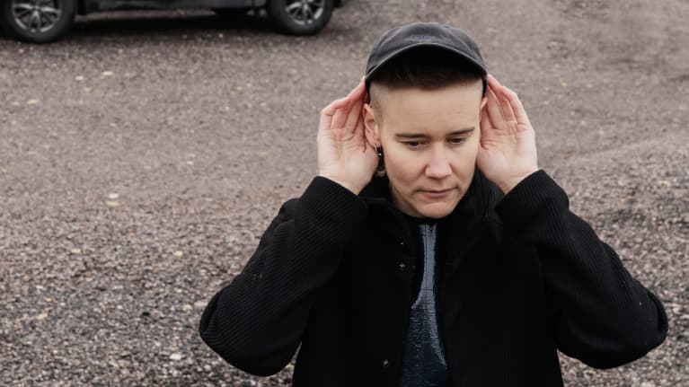 Emilia Kokko kuuntelee ympäristön ääniä parkkialueella lentokentän lähellä.