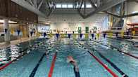 A person swimming in an indoor pool with lanes.