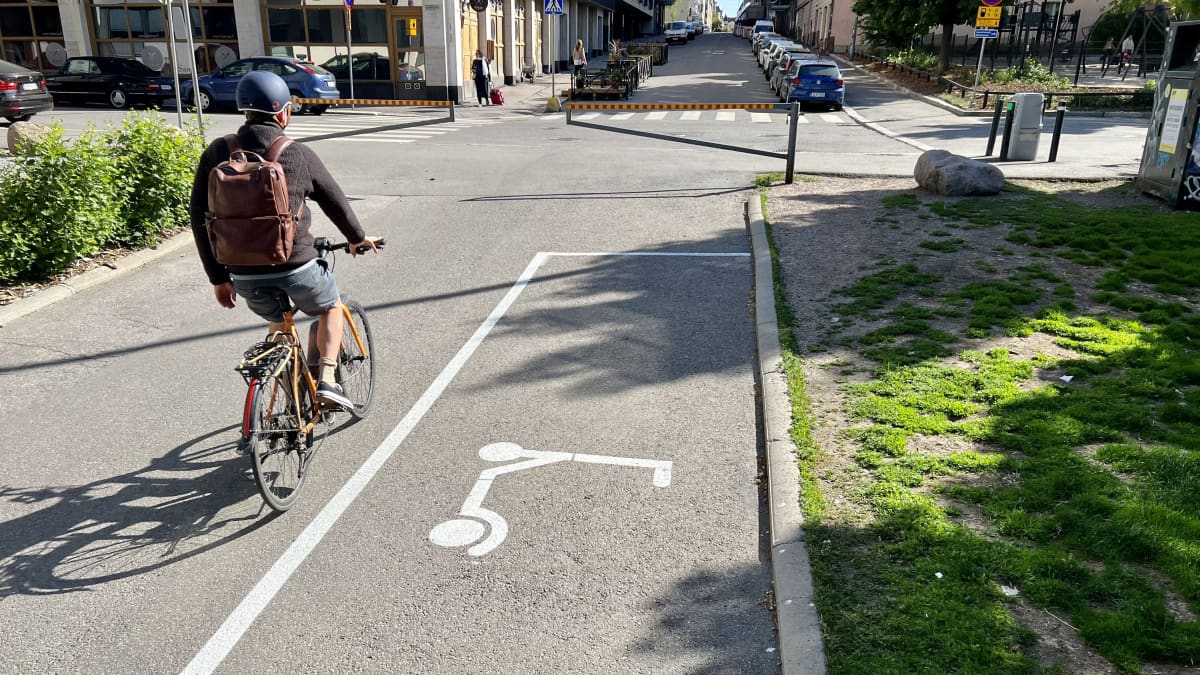Kuvassa sähköpotkulaudan pysäköintiruutu maalattuna asfaltille. Ruudun vieressä polkee pyöräilijä.