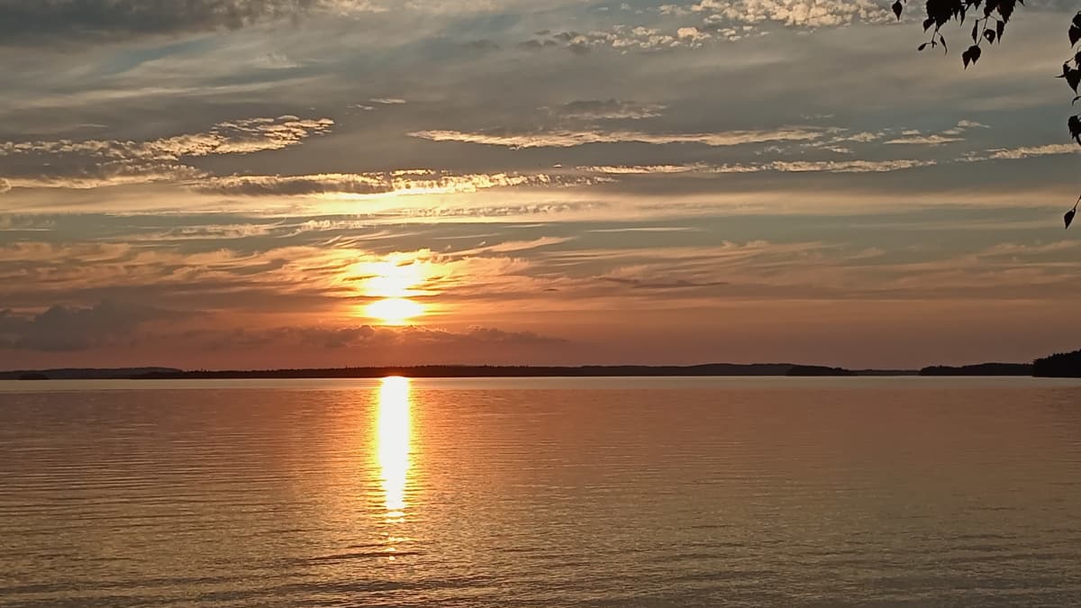 Kuvassa näkyy auringonlasku järven yllä.
