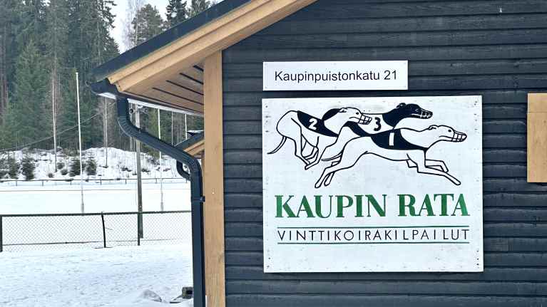 Tampereen Kaupin vinttikoirarata talvella, huoltorakennuksen seinässä piirroskuvataulu koirista. 