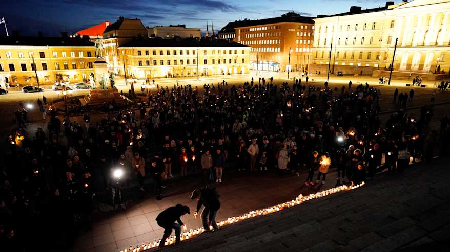 Ihmisiä ja muistokynttilöitä Tuomiokirkon portailla Senaatintorilla.