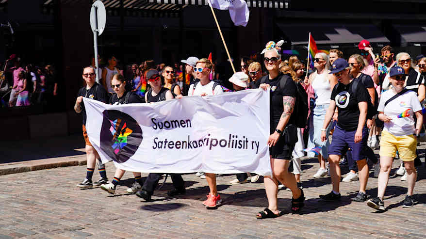 Pride-kulkueen osallistujat kantavat Suomen Sateenkaaripoliisit ry:n kylttiä.