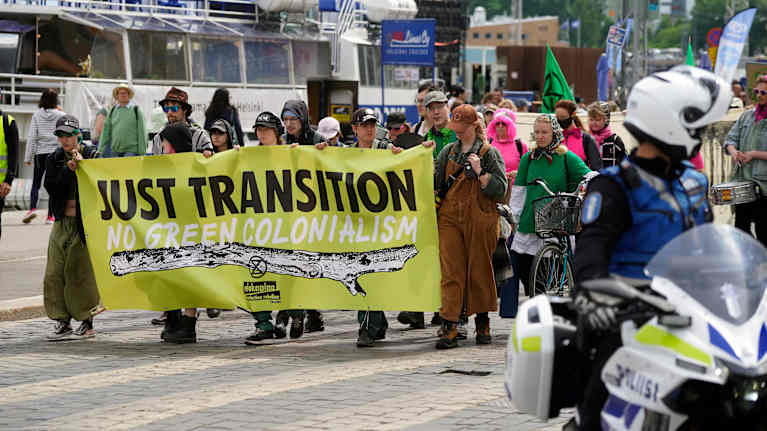 Extinction Rebellion protesters hold banners as they walk through the streets of Helsinki.