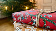 Two wrapped Christmas presents in the foreground with a decorated Christmas tree seen in the background.