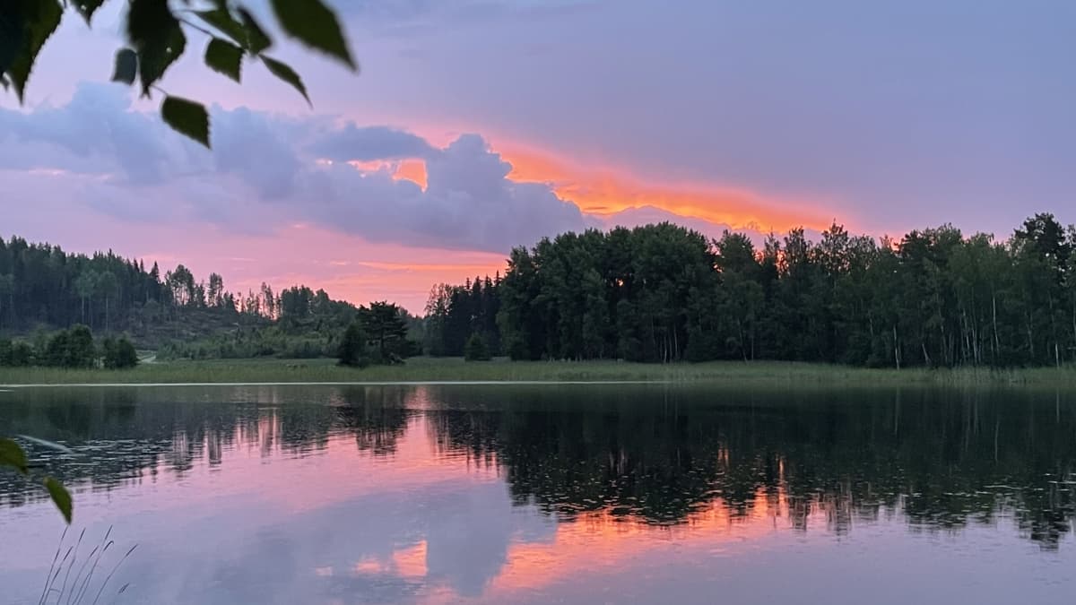 Aurinko kajastaa punertavasi järven yllä aamuyöstä.