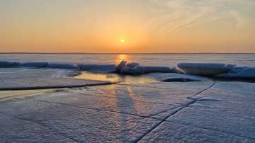Jäinen maisema Pyhäjärveltä. Railo jäässä ja aurinko horisontissa. 