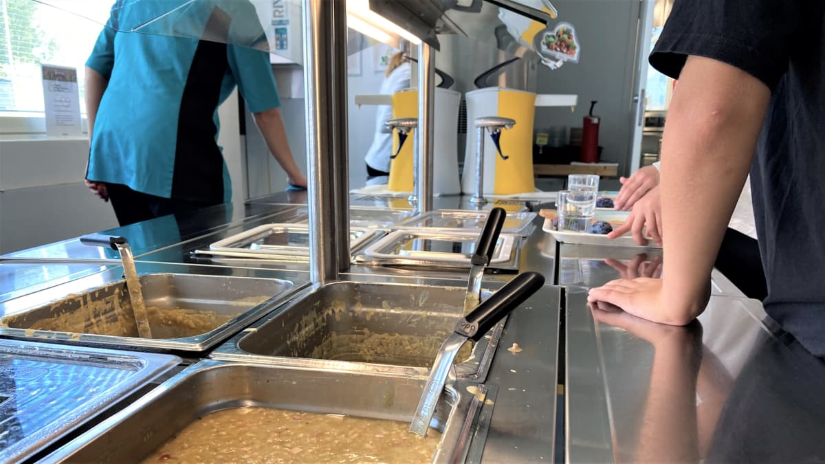 Koulun ruokalan linjastolla on oppilaita ottamassa ruokaa.
