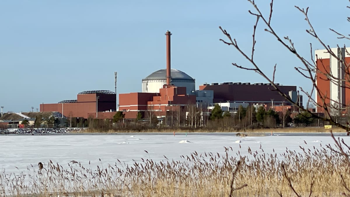 Olkiluodon kolmosreaktori jäätyneen meren vastarannalta aurinkoisessa talvikelissä kuvattuna.