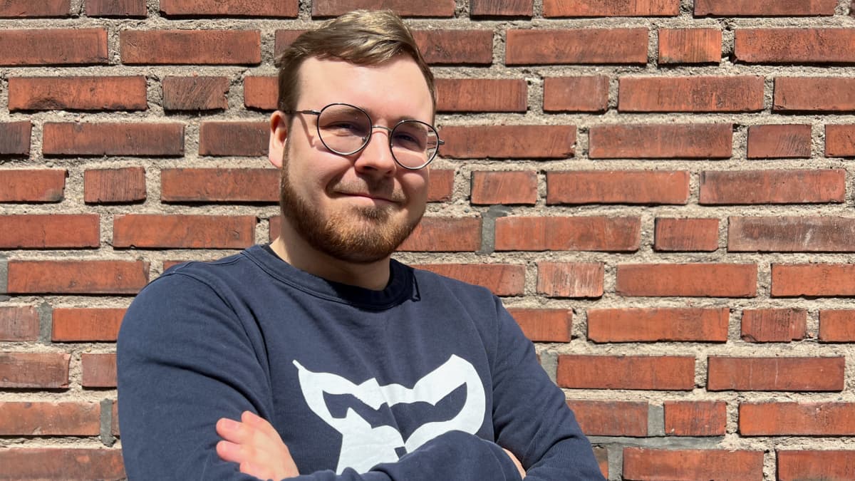 Olli Raudus seisoo punatiiliseinän edessä.