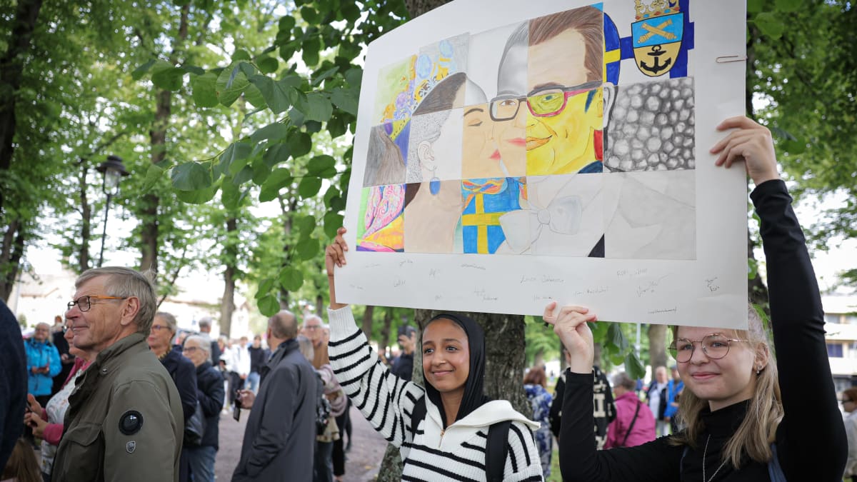 Kaksi nuorta opiskelijaa tervehti kuninkaallisia oman julisteensa kanssa Loviisassa torstaina 21. syyskuuta.
