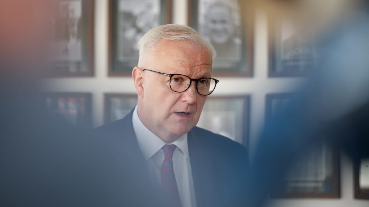 Portrait style photo of Olli Rehn wearing glasses, a white shirt, blue suit jacket and tie.