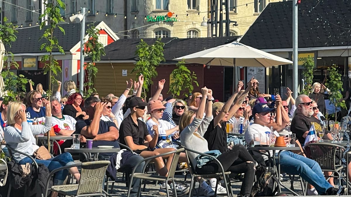 Yleisöä seuraamassa Suomen jääkiekkopeliä Tampereen Keskustorin Kesäkeitaan kisakatsomossa. Osa ihmisistä tuulettaa kädet ilmassa.