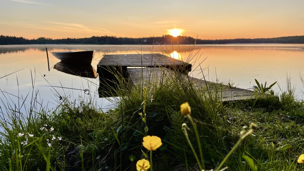 Auringonnousun aikaan. Järvi, laituri, vene ja aurinko matalalla. 