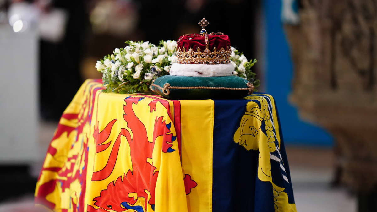 Drottning Elizabeths kista draperad med den brittiska kungliga flaggan i skotsk version. På kistan finns en blomsterhyllning och den skotska kronan vilande på en kudde.
