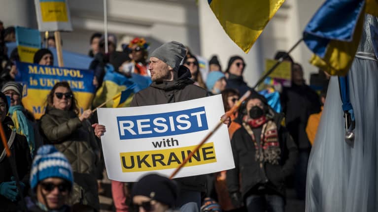 Mielenosoittajia Helsingissä senaatintorilla protestoimassa Venäjän sotatoimia Ukrainassa vastaan. Edustalla mies, joka pitää kylttiä: "Stand with ukraine".