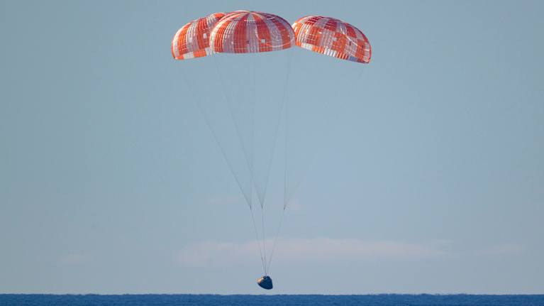 Artemis II lands in the sea, escorted by parachutes.