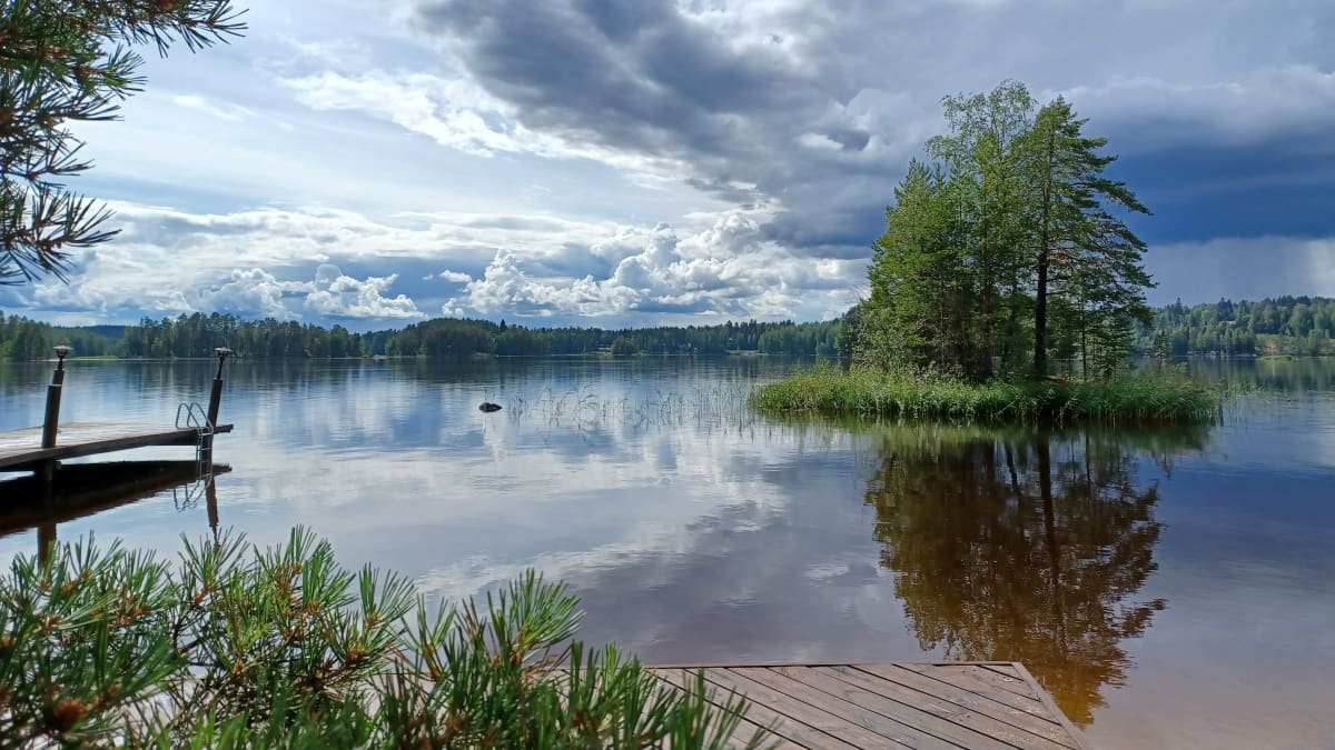 Kuvassa näkyy järvimaisema ja sadekuuroja.